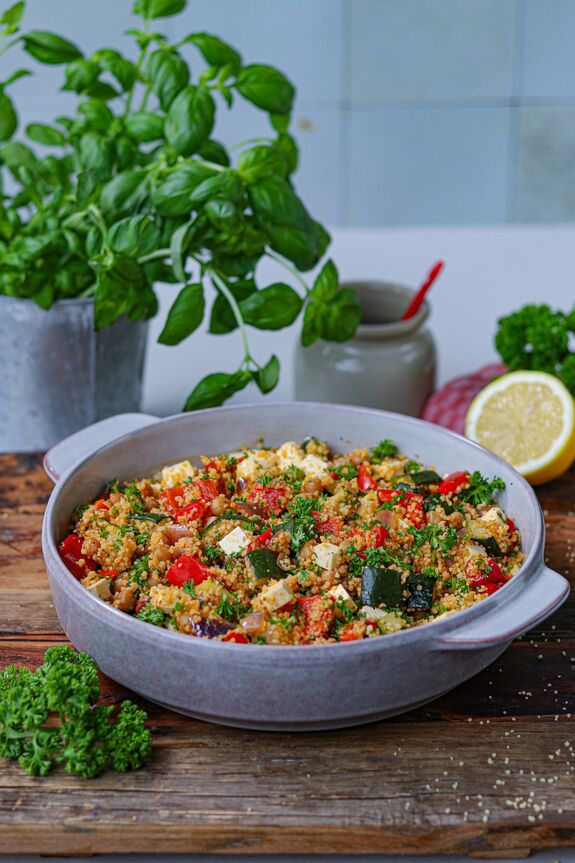 Couscoussalat in Schüssel vor Basilikumstrauch