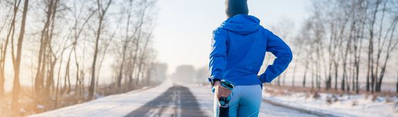 Ein Mann dehnt sich beim Joggen im Winter.