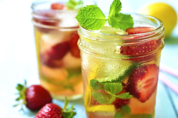 Auf einem Tisch stehen zwei Cocktails mit vielen Früchten darin.