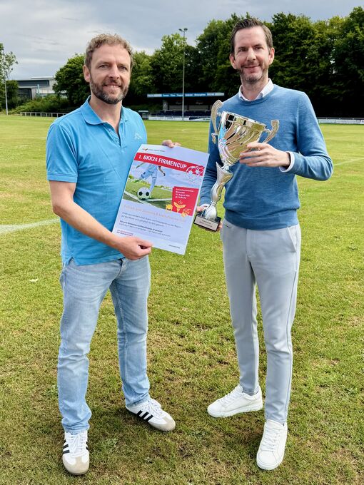 Zwei Männer halten Pokal und Einladung in der Hand