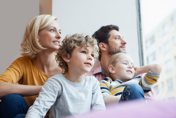 Eine vierköpfige Familie sitzt zusammen und schaut aus dem Fenster.