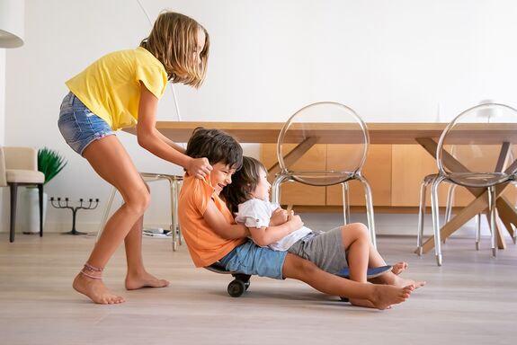 Kinder spielen in der Wohnung mit einem Skateboard