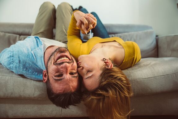 Fröhliches Paar liegt auf dem Sofa.