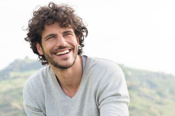 Ein Mann lächelt vor einer schönen Landschaft.