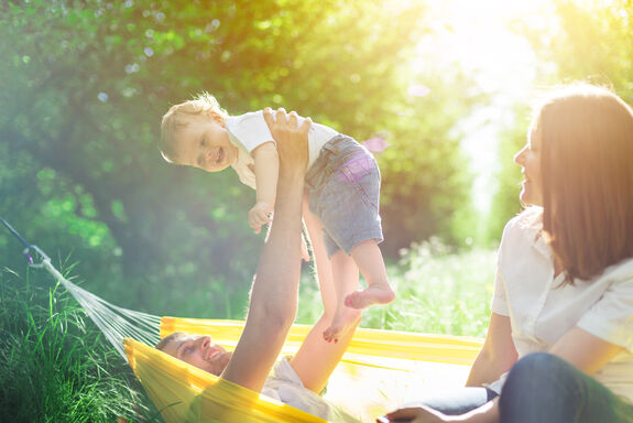 Ein Vater hält glücklich sein Baby in die Luft