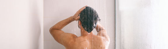 Mann steht unter der Dusche